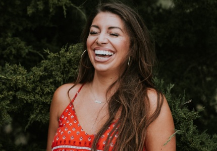 Woman in red sleeveless blouse laughing outdoors